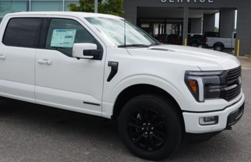 White Ford F-150 pickup truck parked outside a service center.