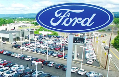 Ford dealership lot filled with various vehicles and the iconic Ford sign.